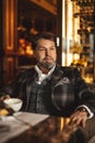 Thoughtful mid-aged businessman drinking coffee and looking away in restaurant Royalty Free Stock Photo