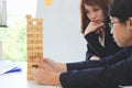 Thoughtful and mindful business woman playing wooden block tower in office. Risk and strategy business concept