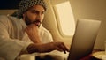 Thoughtful muslim working laptop on business trip closeup. Rich man typing