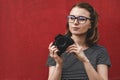 Thoughtful observant young woman photographer over a red wall