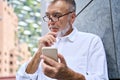 Old senior professional business man holding phone using smartphone thinking. Royalty Free Stock Photo