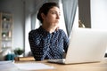 Thoughtful Indian female distracted from computer work looking into distance Royalty Free Stock Photo