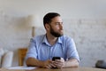 Thoughtful pensive millennial smartphone user man looking away