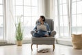 Thoughtful pretty middle aged lady relaxing with laptop in armchair Royalty Free Stock Photo