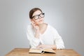 Thoughtful pretty teenage girl in glasses reading book and thinking Royalty Free Stock Photo