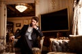 Thoughtful prosperous male involved in business, dressed in formal suit, sits in royal room on comfortable chair, waits