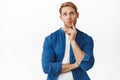 Thoughtful redhead man deep thinking, looking up with pondering face, making choice, standing pensive against white Royalty Free Stock Photo