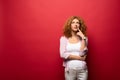 Thoughtful redhead woman gesturing isolated on red