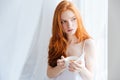Thoughtful redhead woman holding cup with tea