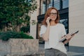 Thoughtful redhead woman looks into distance makes phone call holds smartphone near ear