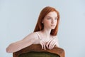 Thoughtful redhead woman sitting on the chair