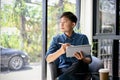 Thoughtful and relaxed Asian man daydreaming about his life while using tablet Royalty Free Stock Photo