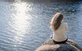 Thoughtful romantic woman sitting on the river bank in sunset in autumn day Royalty Free Stock Photo