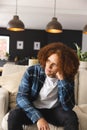 Thoughtful, sad biracial man sitting on couch in living room, looking away, copy space Royalty Free Stock Photo