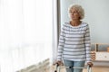 Thoughtful sad injured old woman standing alone using walking frame Royalty Free Stock Photo