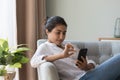 Thoughtful satisfied millennial Indian girl using online shopping app