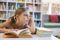 Thoughtful school girl reading book in library Royalty Free Stock Photo