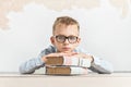 A thoughtful schoolboy sits at a desk with books Royalty Free Stock Photo