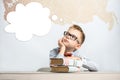 A thoughtful schoolboy sits at a desk with books Royalty Free Stock Photo