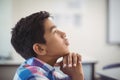 Thoughtful schoolboy sitting in classroom