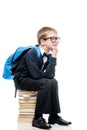 thoughtful schoolboy sitting on a pile of books on a white background Royalty Free Stock Photo