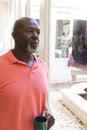 Thoughtful senior african american man having coffee looking out of window at home, copy space Royalty Free Stock Photo