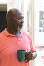 Thoughtful senior african american man having coffee looking out of window at home Royalty Free Stock Photo