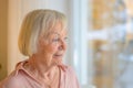 Thoughtful senior lady staring out of a window