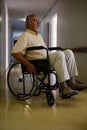 Thoughtful senior man sitting on wheelchair in corridor Royalty Free Stock Photo