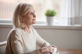 Dreamy aged female enjoying tea remembering pleasant memories