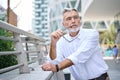 Thoughtful serious older senior business man thinking standing outdoors.