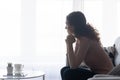 Thoughtful serious woman sitting on couch looking out window Royalty Free Stock Photo