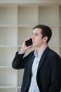 Thoughtful serious young business professional man speaking on cellphone in office, looking away, thinking on Royalty Free Stock Photo