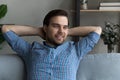 Thoughtful smiling guy relaxing on couch, looking away and smiling