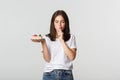Thoughtful smiling pretty girl pondering while holding piece of cake, white background Royalty Free Stock Photo