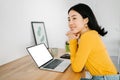 Thoughtful smiling young woman with laptop looking away sitting at home office Royalty Free Stock Photo