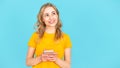 Thoughtful and smiling young woman looking aside, holding modern cellphone