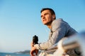 Thoughtful sportsman standing on quay, with bottle of water Royalty Free Stock Photo