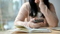 Thoughtful and stressed young Asian female college student holds her phone, hand on chin Royalty Free Stock Photo