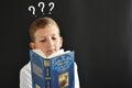 thoughtful student child at the blackboard with a book Royalty Free Stock Photo