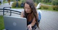 Thoughtful student girl is lying on bench outside and working with laptop, closing it Royalty Free Stock Photo