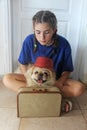 A thoughtful teenage girl with pekingese dog and a suitcase