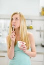 Thoughtful teenager girl eating yogurt in kitchen