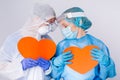 Thoughtful, tired doctors in uniform with big red hearts in their hands. Valentine& x27;s day, charity, giving back, pandemic