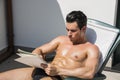 Thoughtful topless young man in deckchair with pencil and notebook Royalty Free Stock Photo