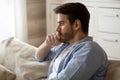 Thoughtful upset man pondering problem solving, sitting on couch