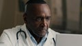 Thoughtful wise experienced mature 50s male african american doctor medical professor general practitioner sit at