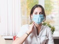 thoughtful woman doctor wearing face mask sitting in front of a window in clinic or hospital. brunette asian woman tired Royalty Free Stock Photo