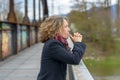 Thoughtful woman gazing out from a bridge