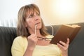 Thoughtful woman holding her glasses and reading a book, light effect Royalty Free Stock Photo